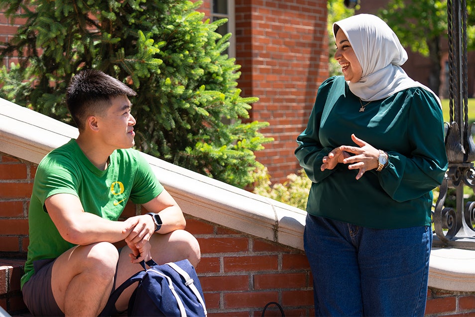 Photo of two students talking on steps.