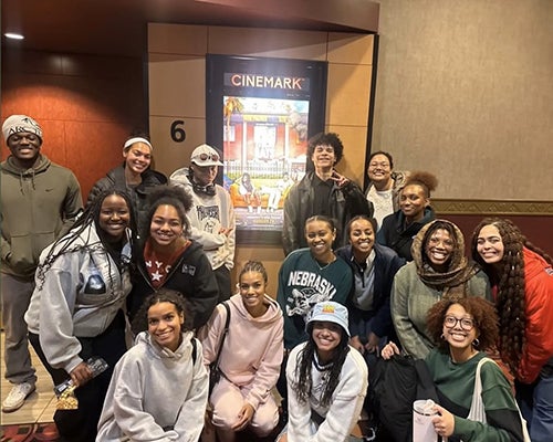 A group of students gather for a photo at a movie theater