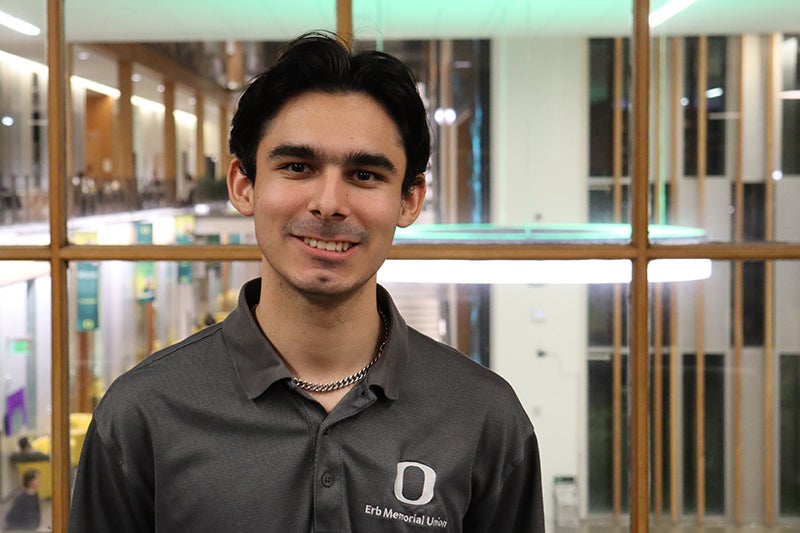 Young man with black hair wearing a black polo shirt
