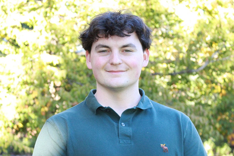 young man with black hair wearing a dark green polo shirt