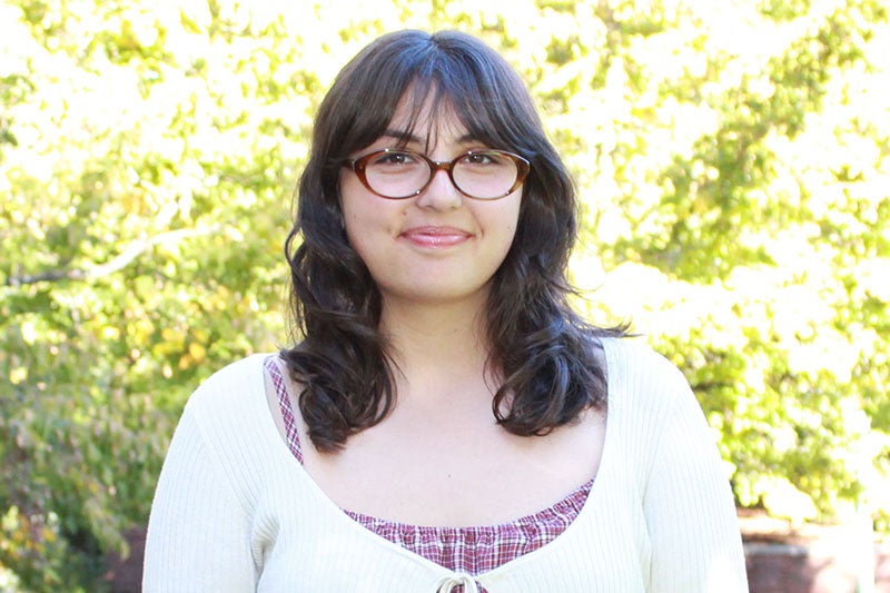 young woman with black hair wearing a white sweater