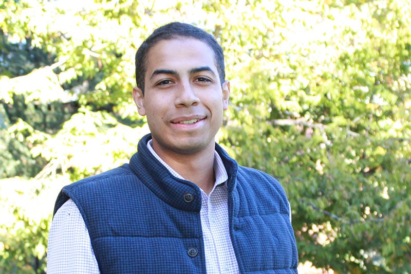 young man with black hair wearing a blue vest
