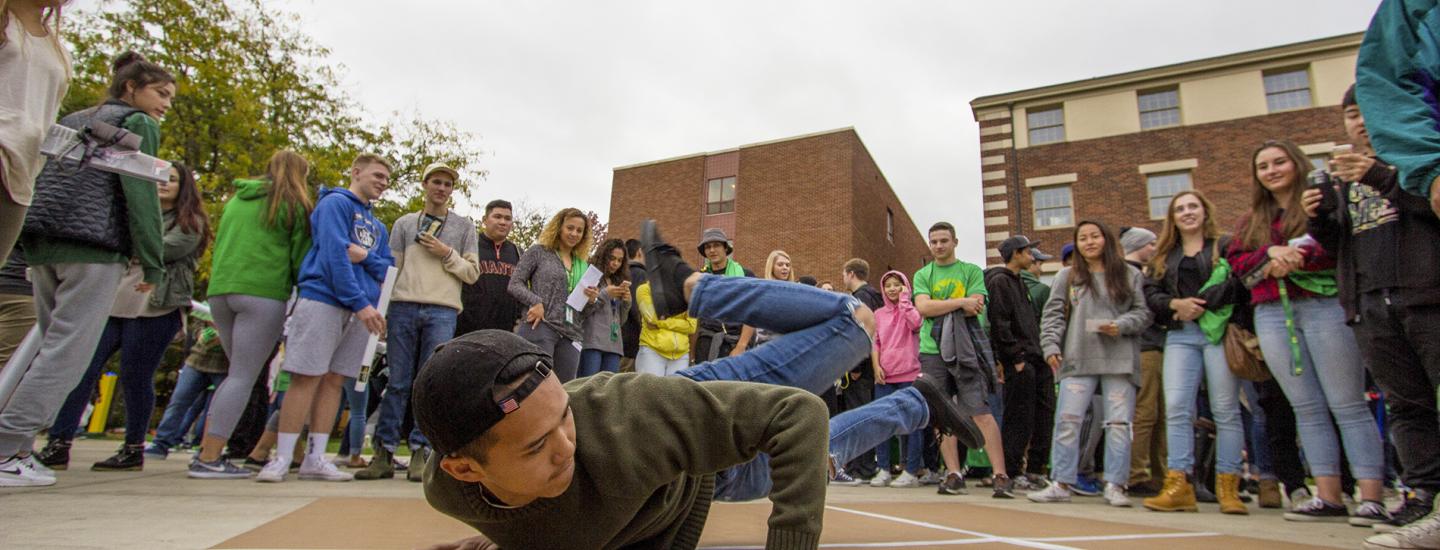 Student breakdancing in middle of crowd.